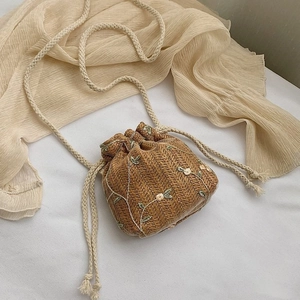 Détail du sac seau en paille tressée avec broderie florale et fermeture à cordon