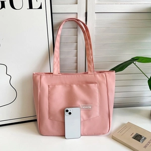 Pink nylon tote bag with front pocket showing size comparison with a smartphone