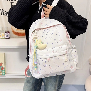 Close-up of white star print backpack with cute moon plush and colorful beaded charms