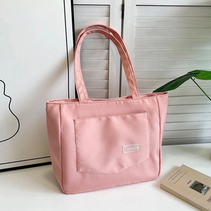 Detail of a pink nylon tote bag with fashion text logo and sturdy reinforced handles