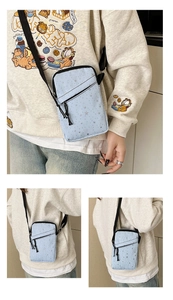 Detail of light blue crossbody phone bag with silver stars and adjustable strap