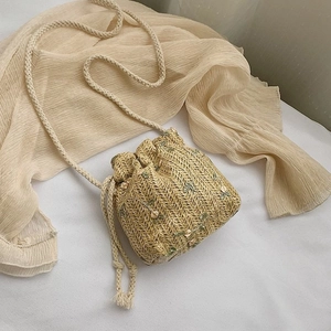 Détail du sac seau en paille avec broderie florale et fermeture à cordon