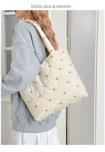 Detail view of quilted tote bag with diamond stitching and embroidered brown bows