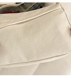 Close-up of beige quilted nylon crossbody bag with textured fabric and zipper detail