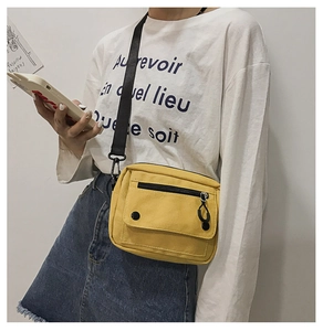 Detail of a mustard yellow canvas crossbody bag with functional double front pockets