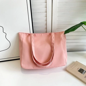 Pink nylon tote bag with dual shoulder straps shown in a minimalist interior setting