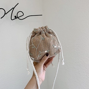 Détail du sac seau en paille avec broderie florale et cordon de serrage en coton blanc
