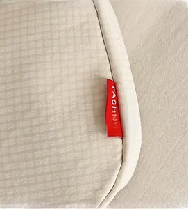 Detailed close-up of a cream nylon bag showing fabric texture and a red 'FASHION' label