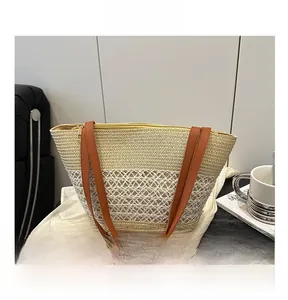 Détail du sac cabas en paille tressée avec lanières en cuir brun et fermeture éclair