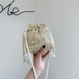 Détail du mini sac seau en paille avec broderie florale rose et cordon de serrage
