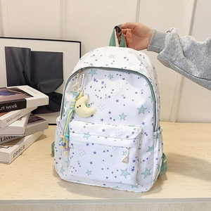Close-up of a white star-patterned backpack featuring a cute yellow moon plush pendant
