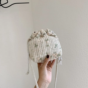 Détail du sac seau en paille avec broderies florales et cordon de serrage pratique