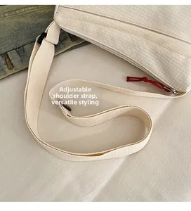 Detail of adjustable nylon strap and red knot zipper on a cream crossbody bag