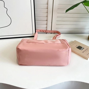 Detailed shot of pink nylon tote bag with white fashion label on a white tabletop