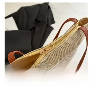 Détail de la fermeture éclair en métal doré et de la texture tressée du sac fourre-tout en paille