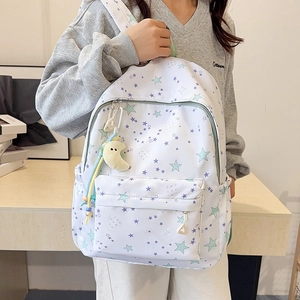 Detail view of white backpack featuring pastel star patterns and a yellow moon plush charm