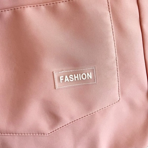 Detail of light pink nylon fabric showing a stitched pocket with a Fashion label