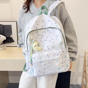 Detail of white star print backpack with green ribbon handle and moon plush accessory