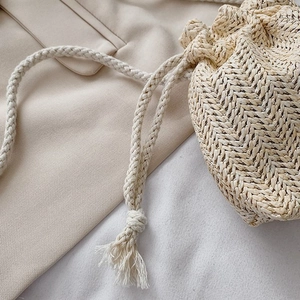 Gros plan d'un sac seau en paille montrant le tissage et le cordon en coton