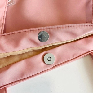 Close-up of magnetic snap closure and pink nylon fabric on this minimalist tote bag