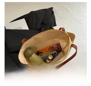 Vue de dessus d'un grand sac cabas en paille montrant le rangement des accessoires