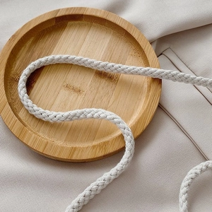 Gros plan sur la sangle tissée crème sur plateau bois pour sac seau en paille