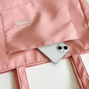 Close-up of pink nylon tote bag front pocket with FASHION label and phone storage detail