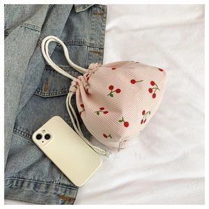 Detailansicht der rosa Cord-Kordelzugtasche mit Kirschmuster und weiß gewebten Griffen