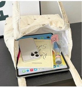 Detail view of spacious beige quilted tote bag interior with books and 10 inch tablet