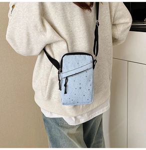 Detail of light blue crossbody phone bag with star prints on casual beige hoodie outfit