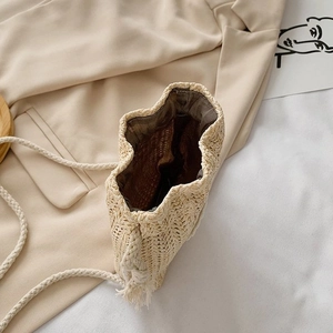 Vue détaillée du sac seau en paille montrant la doublure et la bandoulière cordon