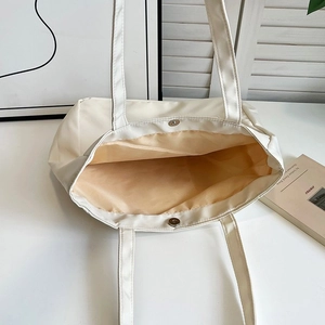 Top view of cream nylon tote bag showing magnetic buckle and spacious interior liner