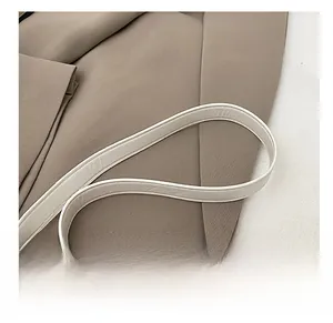 Dettaglio ravvicinato della tracolla in pelle beige con cuciture pulite su una borsa da donna