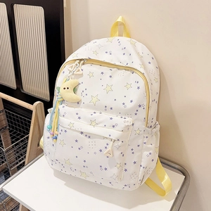 Detail of white star print backpack with yellow straps and moon plush charm