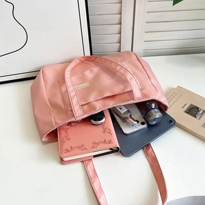Detail of pink nylon tote bag showing front pocket and spacious interior storage