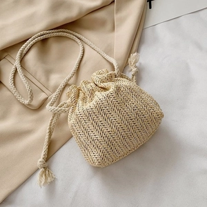 Détail du sac seau en paille tissée avec motif à vagues et bandoulière en corde