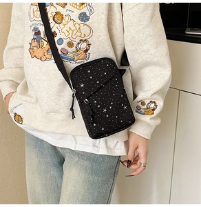 Close-up of black canvas crossbody phone bag with white star pattern and adjustable strap