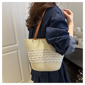 Vue détaillée d'un grand sac fourre-tout en paille avec bandoulière en cuir porté par un mannequin