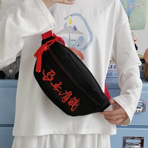 Schwarze Umhängetasche aus Canvas mit roter Stickerei und verstellbarem Gurt am Model