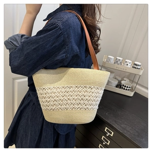 Détail du cabas en paille tissée avec texture ajourée et bandoulière en cuir marron