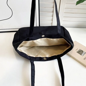 Detail view showing large nylon tote bag interior with magnetic clasp and yellow lining