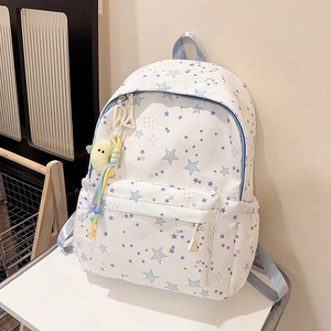 Close-up of white star pattern backpack with blue straps and yellow bird plush charm