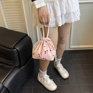 Detail der rosa Kord-Beuteltasche mit roten Kirschmustern und weißem Kordelzugverschluss