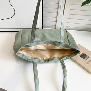 Detail shot of green nylon tote bag showing interior lining and magnetic closure