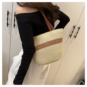 Détail d'un sac cabas en paille avec sangle bohème et anses en cuir sur un mannequin