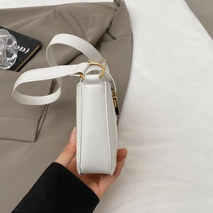 Dettaglio di una borsa a spalla bianca minimalista con hardware dorato e cuciture pulite