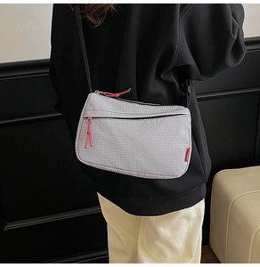 Detail of light grey nylon crossbody bag with red zipper cords and black strap