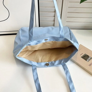 Close-up of light blue nylon tote bag with magnetic clasp and beige lining detail