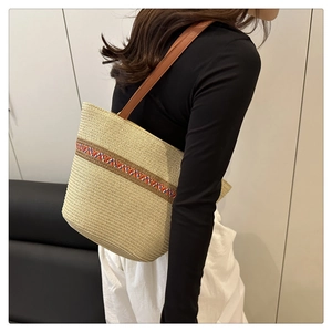 Détail du sac cabas en paille beige avec broderie ethnique colorée et bandoulière en cuir brun