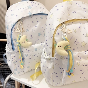 Detail view of white star pattern backpacks with cute moon plush pendants and side pockets